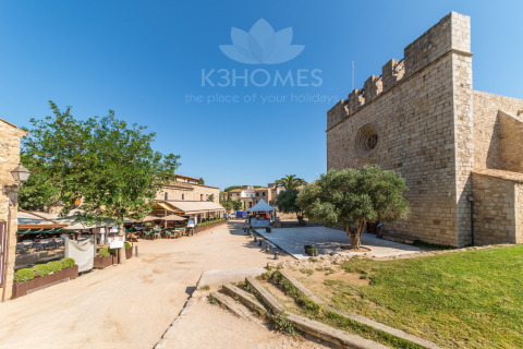 Photo of a glamping site with historic stone buildings, green space, trees, and outdoor dining area.