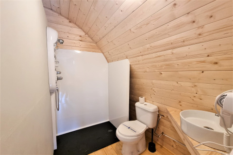Modern bathroom in the Nomad Paraiso pod in Spain with wooden walls, shower, toilet, and sink.
