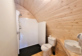 Modern bathroom in the Nomad Paraiso pod in Spain with wooden walls, shower, toilet, and sink.