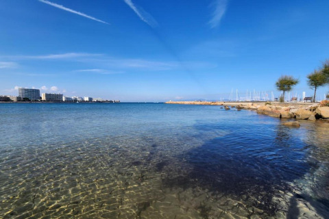 View from a glamping accommodation of clear sea, marina, hotels, and blue sky on a sunny day.