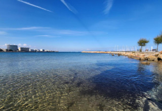 View from a glamping accommodation of clear sea, marina, hotels, and blue sky on a sunny day.