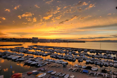 Sunset view at Nomad Paraiso marina in Spain, showing boats docked and calm waters reflecting the sky.