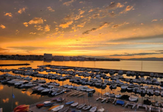 Sunset view at Nomad Paraiso marina in Spain, showing boats docked and calm waters reflecting the sky.