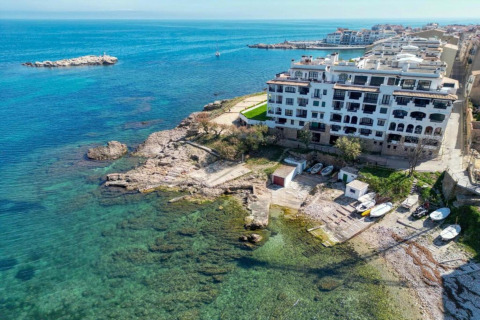 Aerial view of Nomad Paraiso in Spain, featuring seaside buildings, clear blue water, and small boats.