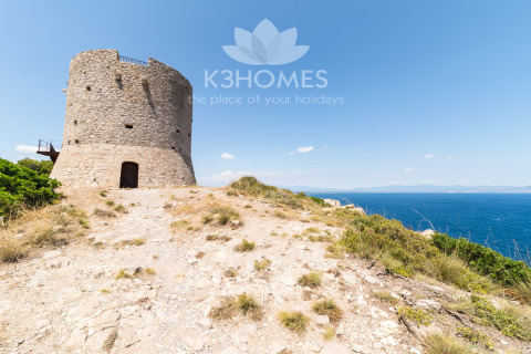 Stone tower overlooking the sea on a rugged coastline, ideal for scenic and unique glamping stays.