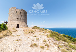 Stone tower overlooking the sea on a rugged coastline, ideal for scenic and unique glamping stays.