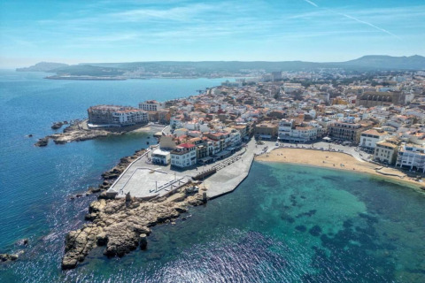 Aerial view at Nomad Paraiso in Spain, showing a coastal town with turquoise waters and seaside buildings.