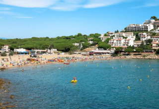 Photo of Nomad Paraiso beach in Spain with tourists, colorful umbrellas, and white buildings on a hill.