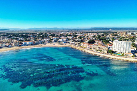 Aerial view of the Nomad Paraiso pod in Spain, showing turquoise waters and a coastal city under clear skies.