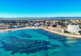 Aerial view of the Nomad Paraiso pod in Spain, showing turquoise waters and a coastal city under clear skies.