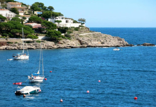 Nomad Paraiso coast in Spain with boats moored in blue water, white villas, and lush green trees.