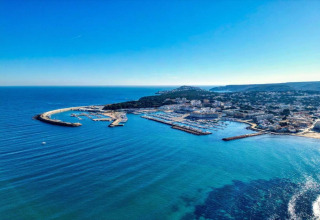Aerial view of the marina and coastline at Nomad Paraiso in Spain, featuring clear blue water and buildings.