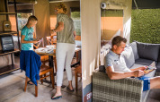 Familie verbringt Zeit in einem Safari-Zelt, mit Aktivitäten am Tisch und Entspannung auf dem Sofa.