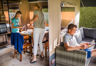 Een familie brengt tijd door in een safaritent, lezend op de sofa en activiteiten aan de tafel.