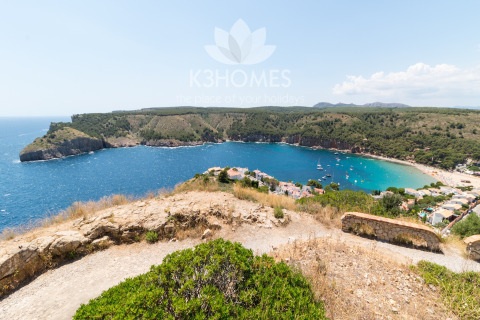 Stunning view over Nomad Paraiso, Spain, with turquoise water, green hills, and boats in the bay.