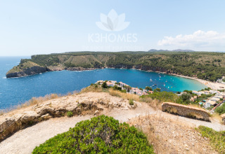 Stunning view over Nomad Paraiso, Spain, with turquoise water, green hills, and boats in the bay.