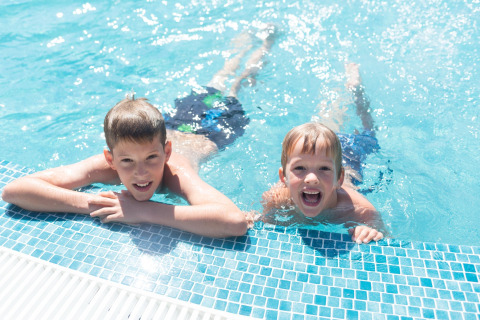 Twee kinderen plezier maken aan het zwembad van Resort «Begur 1» in Spanje op een zonnige dag.