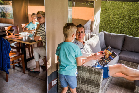 Gezin geniet samen van luxe in een safaritent, met comfortabele lounge en eettafel binnen.