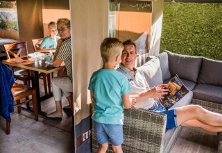 Famille profite d'un moment ensemble dans une tente safari, salon confortable et table à manger.