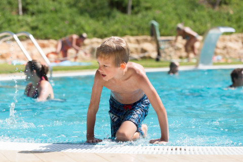 Een jongen komt uit het zwembad bij Resort Begur 1 in Spanje, met andere gasten op de achtergrond.