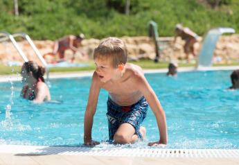Ein Junge steigt aus dem Pool im Resort Begur 1 in Spanien, mit anderen Gästen im Hintergrund.