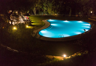 Verlichte buitenzwembad en tuinrestaurant bij nacht in Resort Begur 1 in Spanje, omringd door groen.
