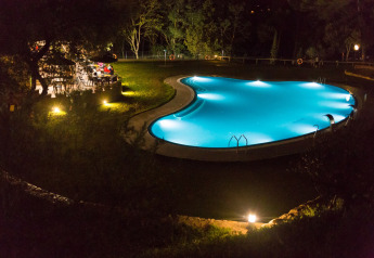 Beleuchteter Swimmingpool und Gartenrestaurant bei Nacht im Resort Begur 1 in Spanien im Grünen.