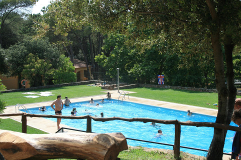 Buitenzwembad met spelende mensen, omringd door groen, bij Resort Begur 1 in Spanje.