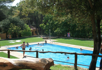 Außenpool mit Menschen, umgeben von Bäumen und Rasen im Resort Begur 1 in Spanien.