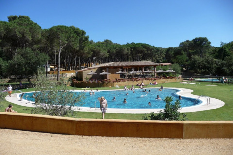 Zwembad met vakantiegangers aan Resort Begur 1 in Spanje, omringd door bos en zonnige faciliteiten.