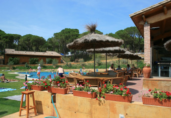 Außenpoolbereich im Resort «Begur 1» in Spanien, mit Menschen, Sonnenschirmen, Blumen und Bäumen.