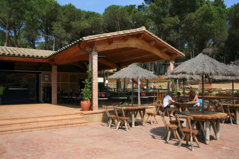 Buitenruimte met houten tafels, stroparasols en een terras bij Resort Begur 1 in Spanje.
