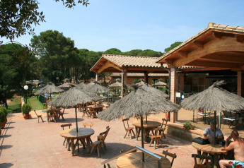 Außenterrasse im Resort Begur 1 in Spanien mit Strohdächern, Holztischen und grüner Umgebung.