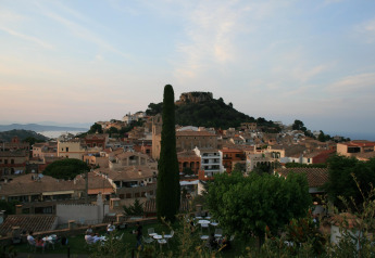 Blick vom Resort «Begur 1» in Spanien auf die Stadt Begur mit Burg, Hügeln und Meer im Hintergrund.
