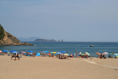 Zicht vanaf safaritent Resort Begur 1 in Spanje met zonnebaden, parasols en uitzicht op de zee.