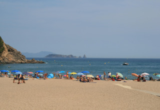 Zicht vanaf safaritent Resort Begur 1 in Spanje met zonnebaden, parasols en uitzicht op de zee.