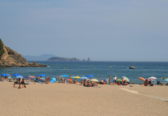 Strandblick beim Resort Begur 1 in Spanien mit Sonnenschirmen, Badegästen und Blick auf das Meer.