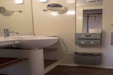 Salle de bain avec lavabo moderne, miroir et étagères dans une tente safari au Resort «Begur 3» en Espagne.