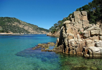 Côte rocheuse et eaux claires au Resort Begur 3 en Espagne sous un ciel bleu éclatant et ensoleillé.