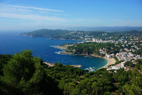 Vue panoramique depuis Resort Begur 3 en Espagne, montrant la côte, la plage et la ville entourée d’arbres.