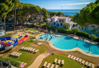 Camping Interpals Bungalow Sa Riera i Spanien med swimmingpool, vandrutsjebane og liggestole under træer.