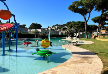 Piscine extérieure pour enfants avec jeux d'eau colorés au CAMPING INTERPALS- Bungalow Sa Riera, Espagne, sous les pins.