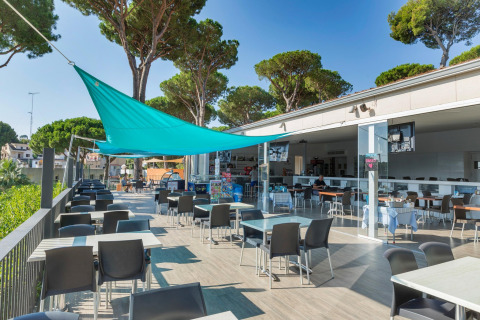 Udendørs spiseområde på Camping Interpals Bungalow Sa Riera i Spanien med blå solsejl og bordopsætning.