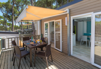 Buitenterras met tafel en stoelen bij CAMPING INTERPALS- Bungalow Sa Riera, tussen de dennen.