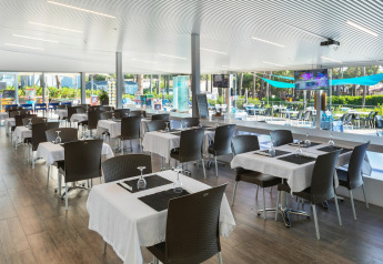 Moderne eetzaal in CAMPING INTERPALS- Bungalow Sa Riera, Spanje, met gedekte tafels en zicht op de tuin.