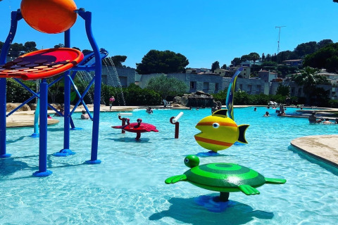 Billedet viser en børnevenlig swimmingpool med farverige vandlegepladser på Camping Interpals i Spanien.