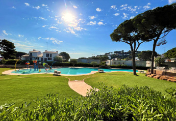 Vue ensoleillée sur la piscine et la pelouse du CAMPING INTERPALS- Bungalow Sa Riera en Espagne.