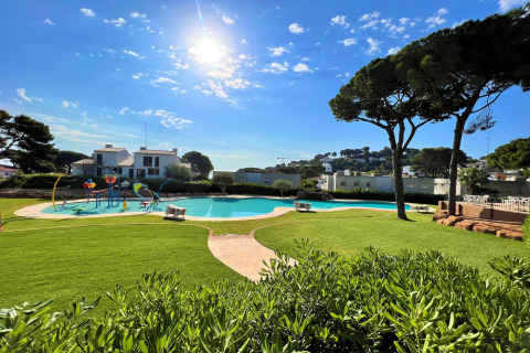 Solrig udsigt over poolområdet og grønne græsplæner på CAMPING INTERPALS- Bungalow Sa Riera i Spanien.