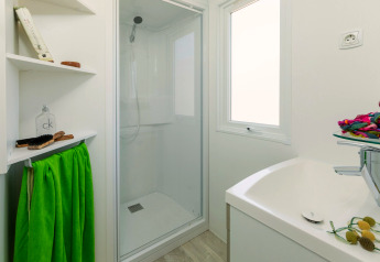 Salle de bain moderne au CAMPING INTERPALS- Bungalow Sa Riera, Espagne, avec douche et serviette verte.