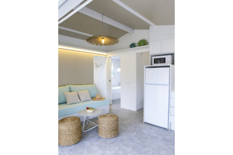 Moderne opholdsstue i Tamarit Park Resort 1 THALASSA med sofa, fletskamler og tekøkken, Spanien.